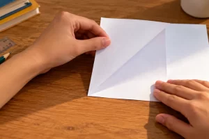 Unas manos doblan una esquina de papel haciendo coincidir sus dos bordes.