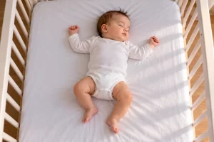 Bebé dormido boca arriba en una cuna sin objetos sueltos.