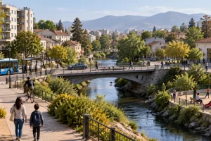Barrio junto a un río con puente, viviendas y transporte.
